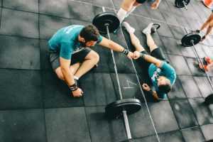 Home Fitnesscoach helpt sporter bij training - goede trainer demonstreert correcte techniek